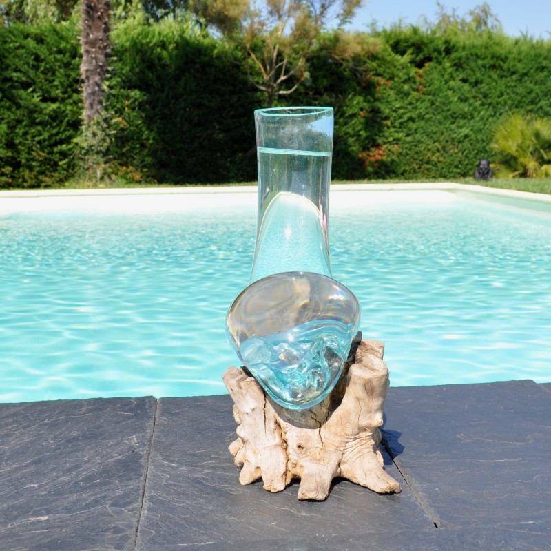 Un vase en verre recyclé moulé en fusion sur du bois flotté de teck