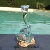 Un soliflore tortueux en verre soufflé et moulé sur du bois flotté