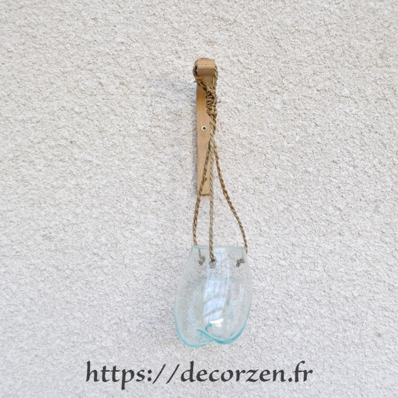 Un merveilleux vase mural en verre recyclé soufflé sur une racine.