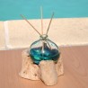 Un diffuseur de parfum en verre recyclé soufflé en fusion sur du bois flotté